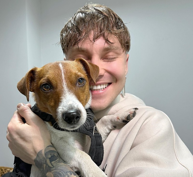 Артем Пивоваров усміхається, тримаючи на руках собаку породи джек-рассел-тер'єр - Патрон.